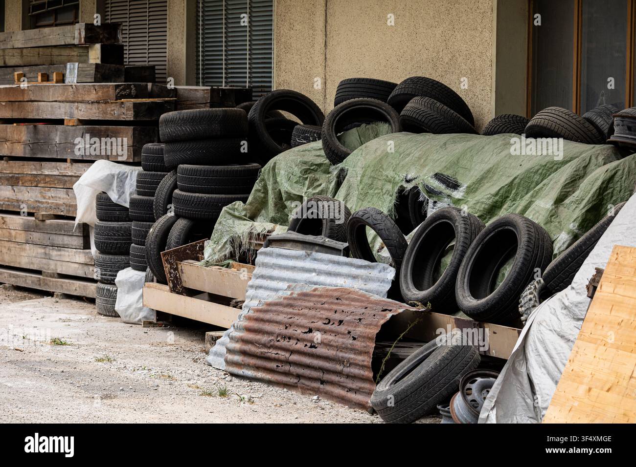Cumulo di pneumatici usati per veicoli conservati in un cortile industriale, in attesa di riciclaggio o smaltimento. Concetto di gestione ambientale e dei rifiuti. Foto Stock