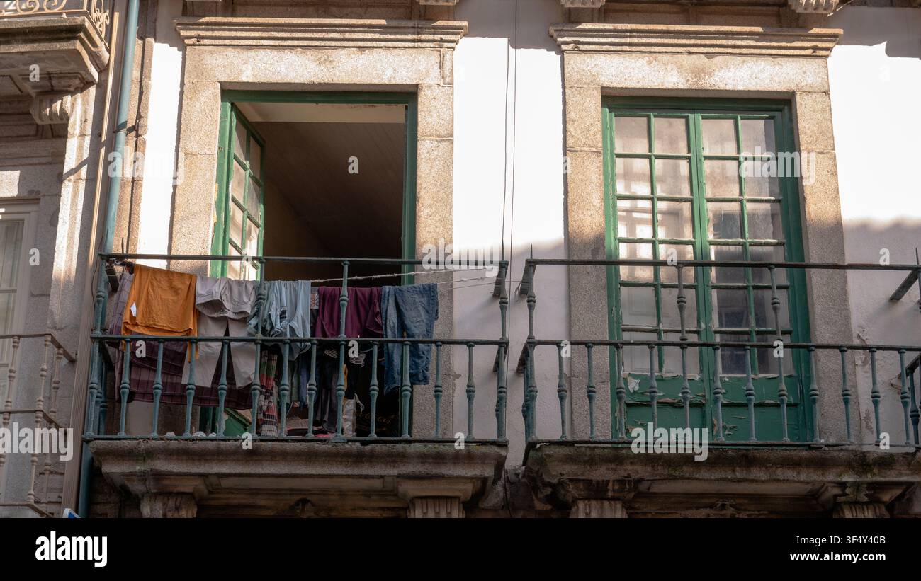 Biancheria che si asciuga su un balcone di ferro di una vecchia casa cittadina con persiane verdi, Porto, Portogallo Foto Stock