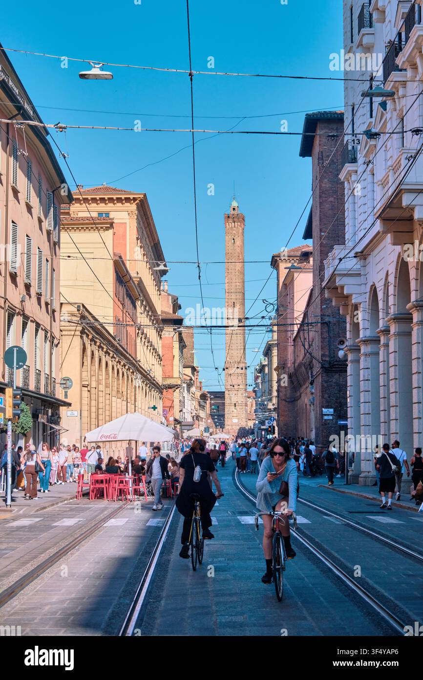 Bologna, Italia - Maggio 2026: Persone in bicicletta su Via Rizzoli verso l'iconica Torre Asinelli Foto Stock