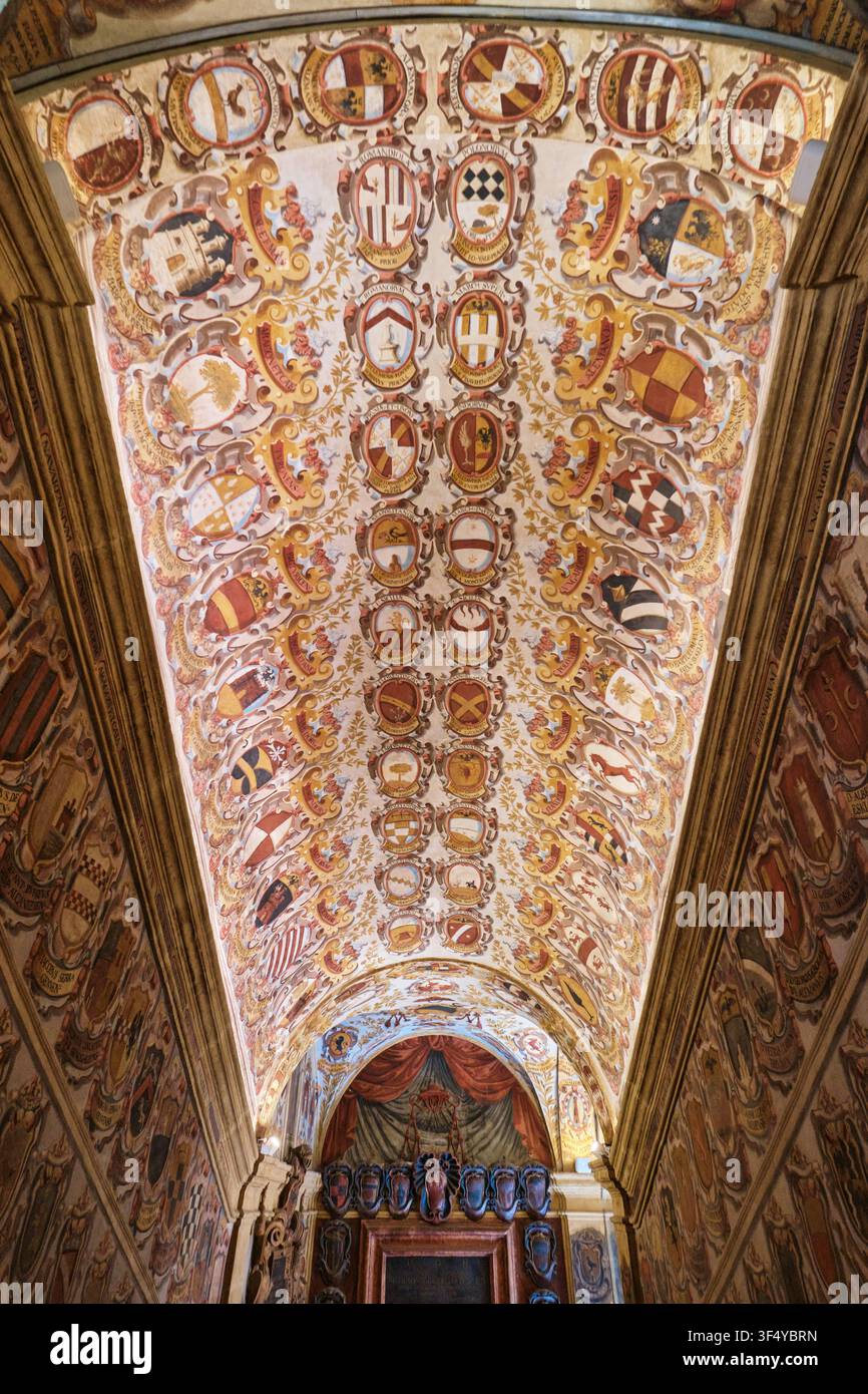 Bologna, Italia – Maggio 2026: Scala storica e soffitto a volta decorati con stemmi araldici nel Palazzo Archiginnasio Foto Stock