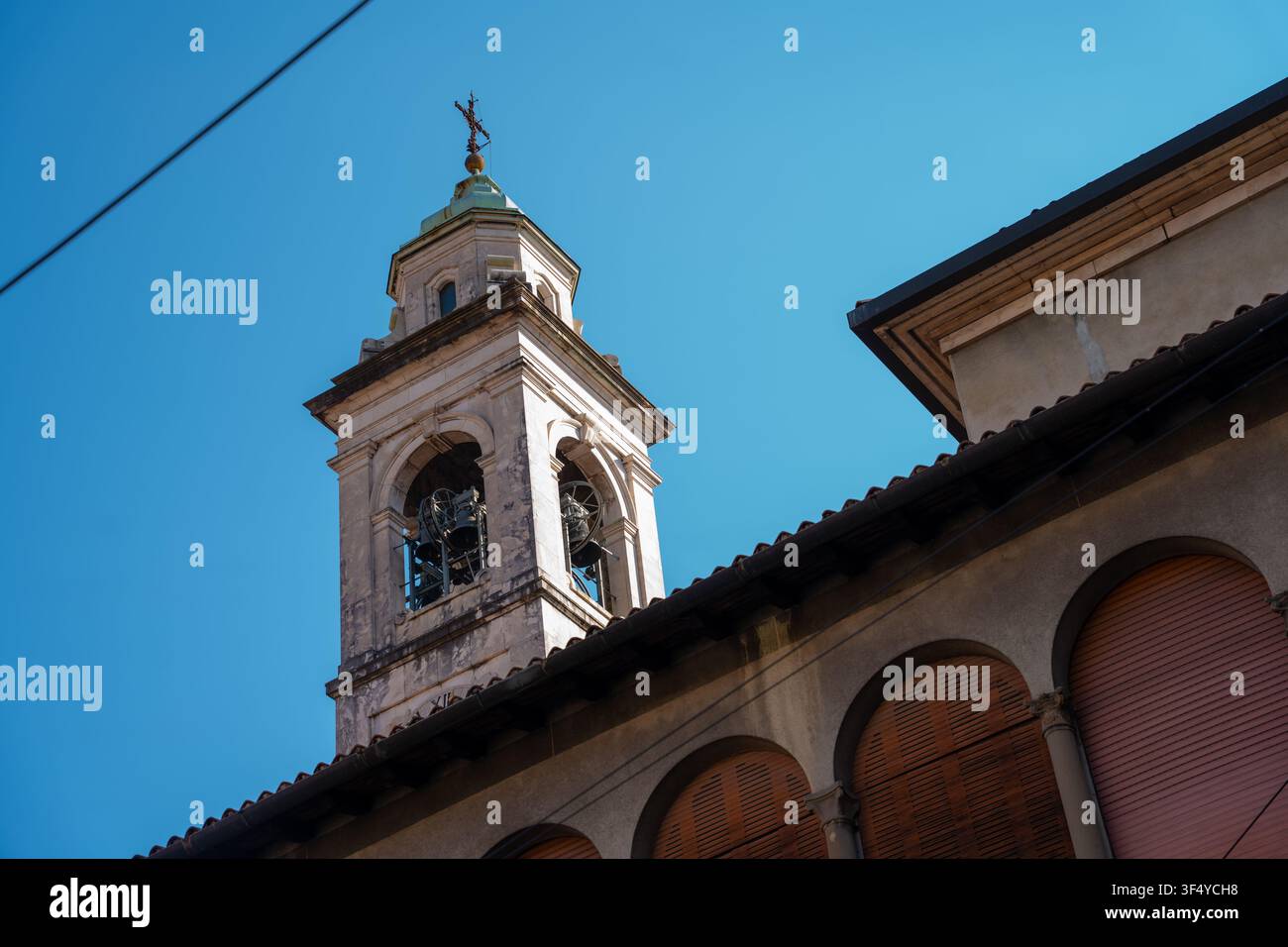 Bergamo, Italia - 16 giugno 2026: Vista architettonica a bassa angolazione di un antico campanile di chiesa italiano contro un cielo blu vivace. Catturato alla luce naturale del giorno Foto Stock