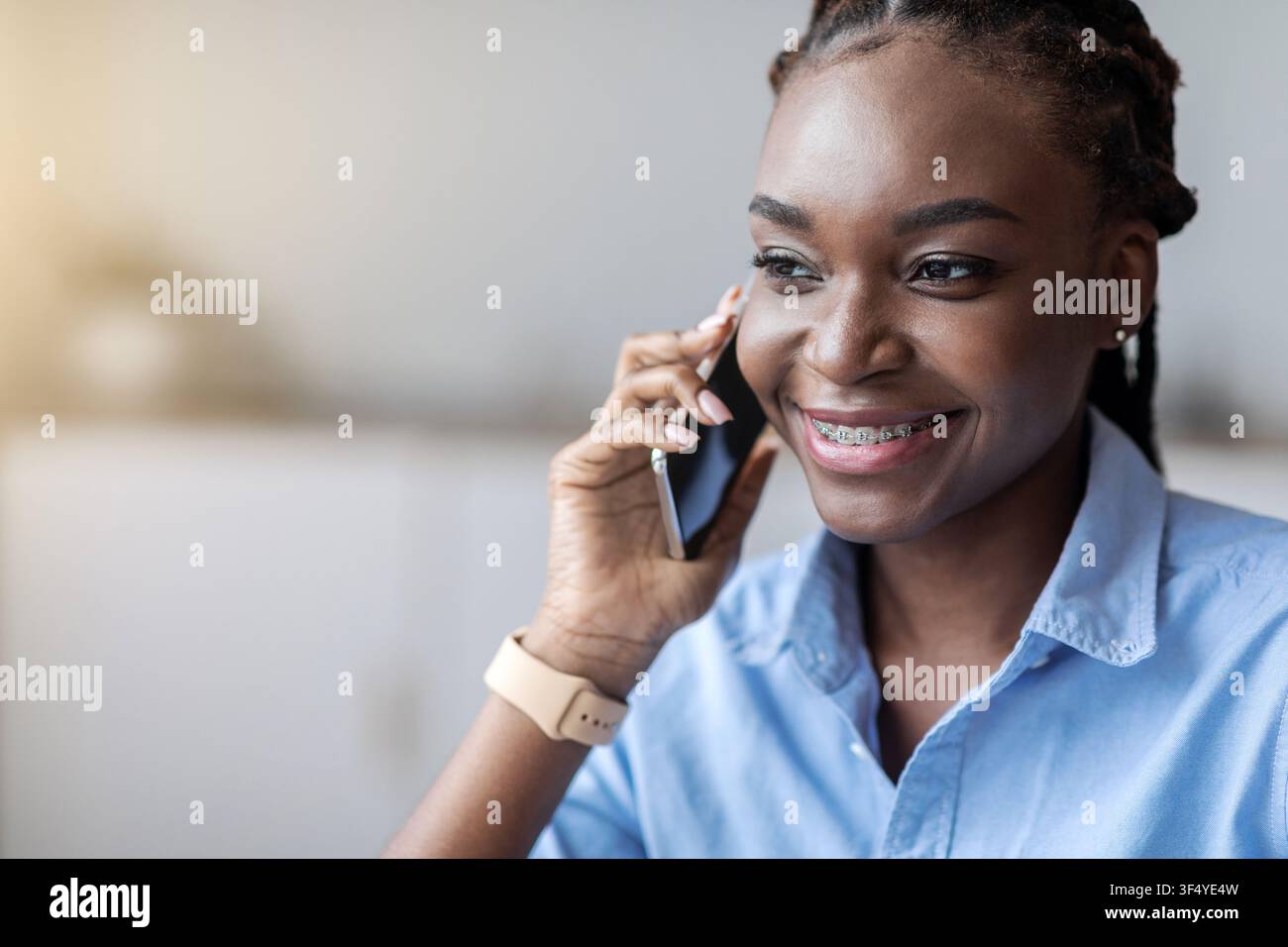 Chiamata telefonica. Donna afroamericana sorridente con parentesi graffe che parlano su Cellphone Foto Stock