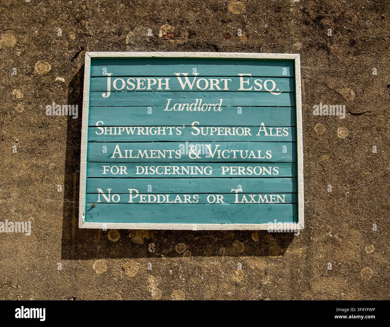 Insegna da pub vintage in legno blu turchese con la scritta Joseph Wort Esq Landlord Shipwrights' Superior Ales montata su un muro di pietra a Bucklers Hard, Hampshire Foto Stock