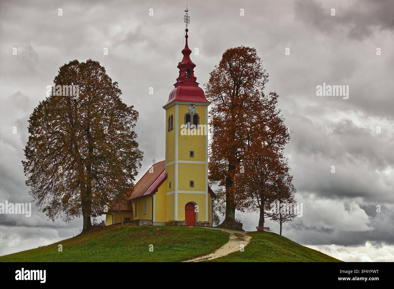 194 Due tigli dai colori autunnali incorniciano la chiesa barocca di San Tommaso del XVII secolo (Cerkev svetega Tomaza) nel villaggio di Gorenji Vrsnik. Idrija-Slovenia. Foto Stock