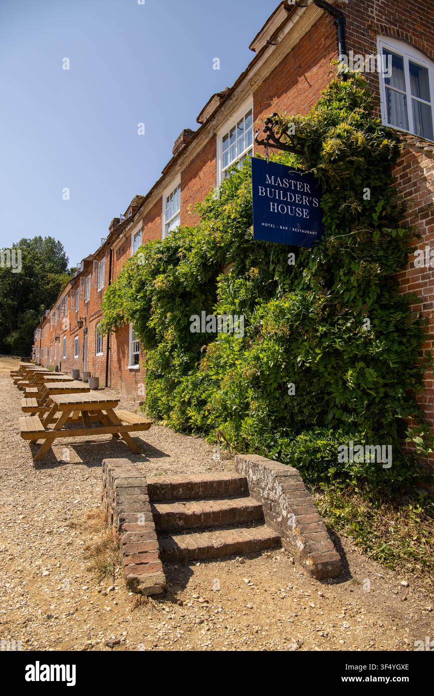 La storica locanda in mattoni rossi Master Builders House a Bucklers Hard nel Hampshire con l'edera verde rigogliosa e tavoli da picnic all'esterno in una giornata di sole Foto Stock