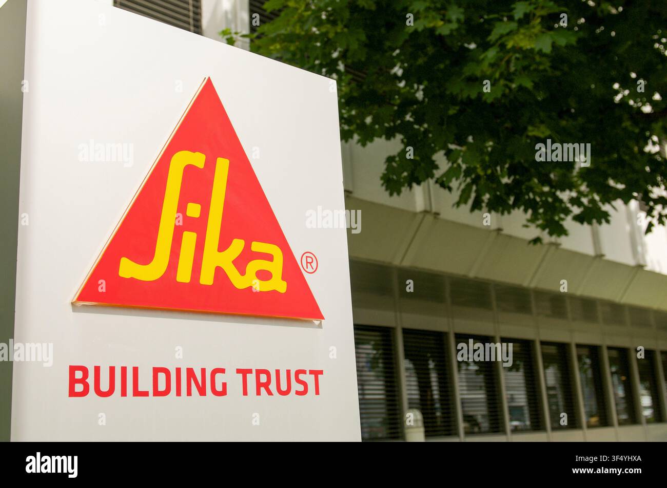 Baar, Zug, Svizzera - 16 giugno 2026: Vista ravvicinata del logo rosso triangolare dell'azienda Sika con lo slogan Building Trust sul cartello d'ingresso Foto Stock