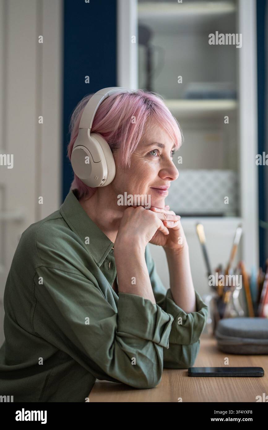 Donna allegra con cuffie che ascolta con piacere podcast online o playlist di musica sullo smartphone. Foto Stock