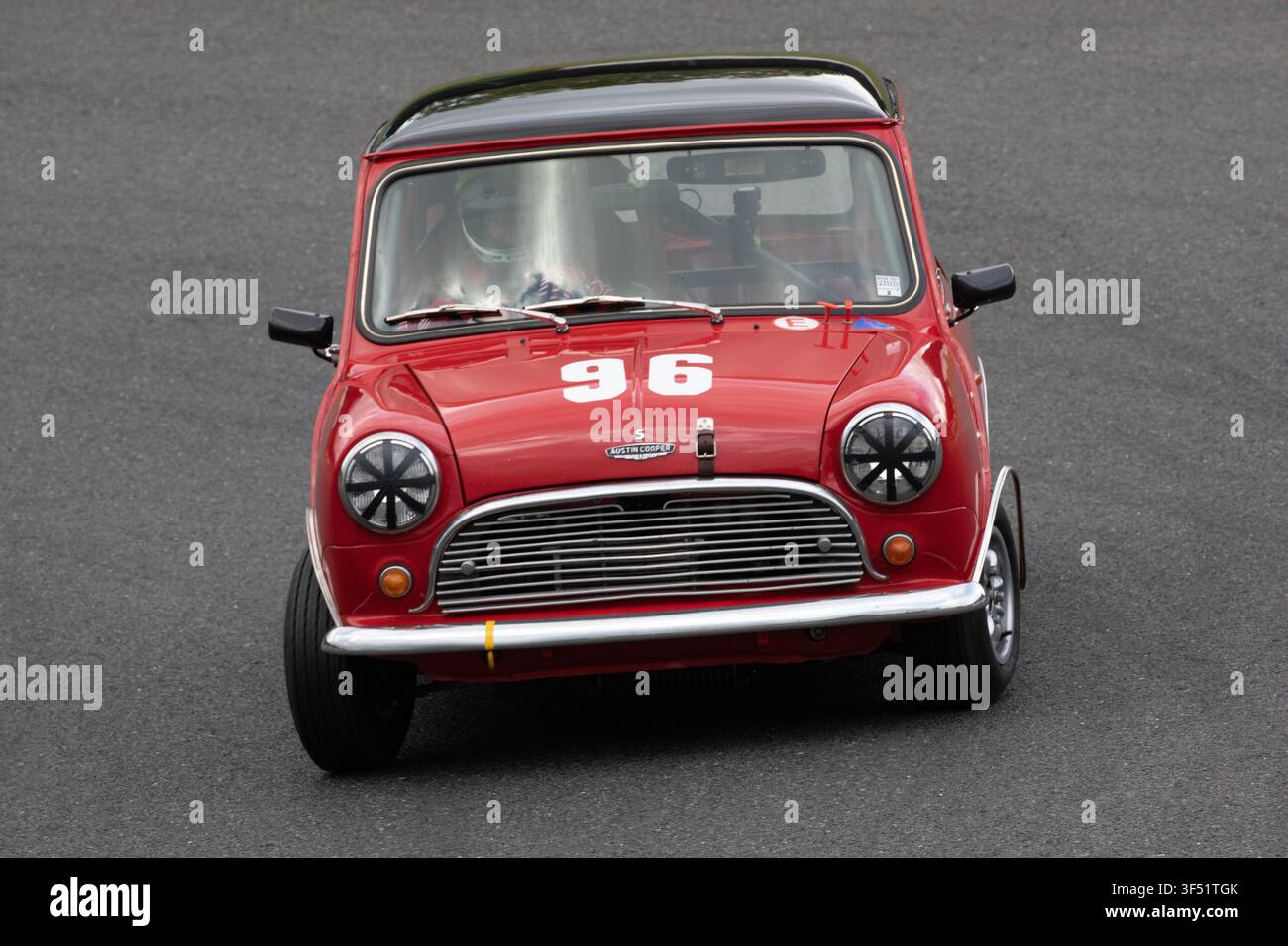 Un'auto da corsa storica Morris Mini Cooper berlina rossa con il numero 96 che affronta una curva su una pista asfaltata durante un evento di sport motoristico classico Foto Stock