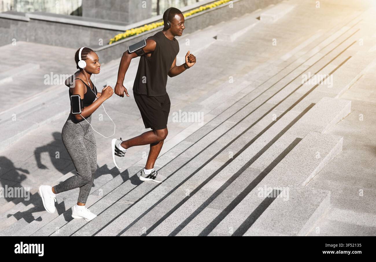 Allenamento cardio. Sorridente coppia africana che fa jogging sui gradini di Urban Park Foto Stock