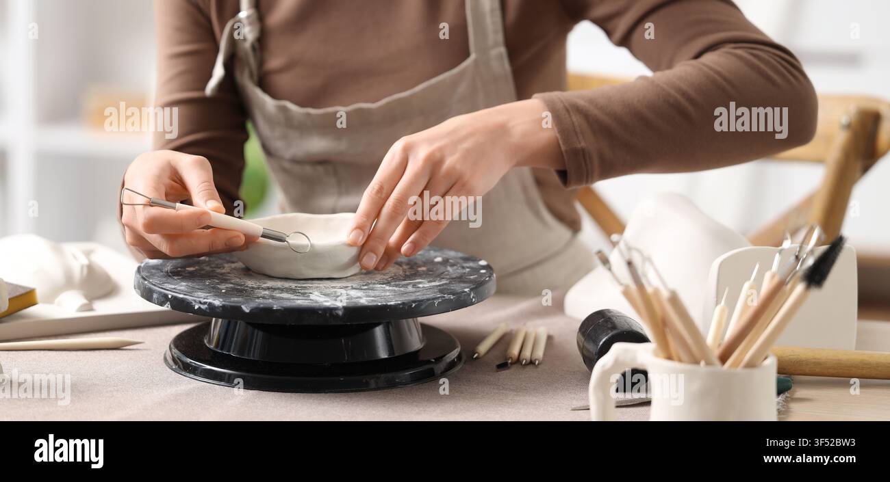 Mani di una donna che modella una ciotola di argilla su un tornio da vasaio con strumenti di scultura, hobby creativo e artigianalità, vari strumenti di scultura sono visibili sul Foto Stock