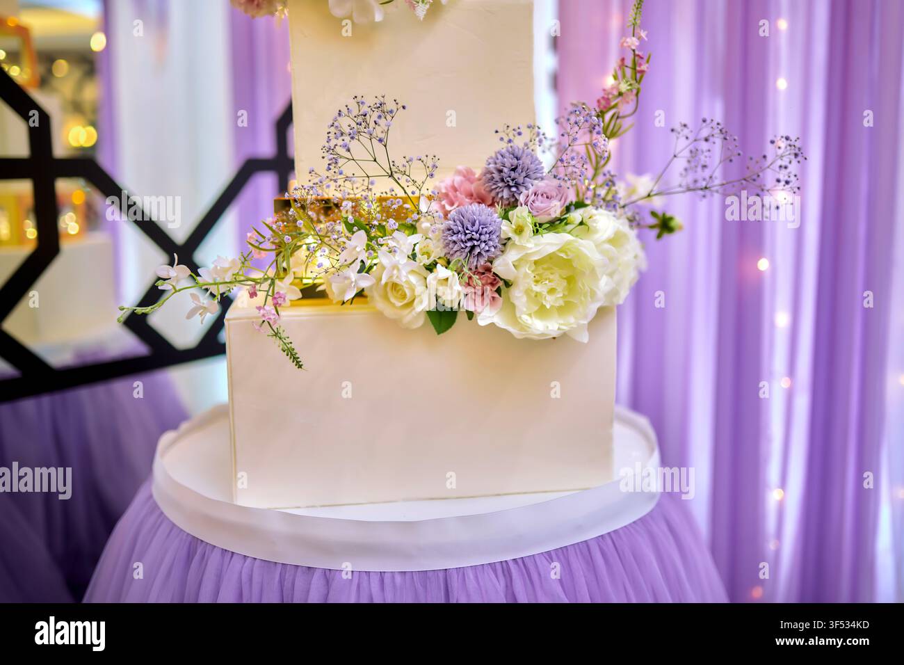 Elegante torta nuziale bianca a tre piani con fiori freschi – Dessert per ricevimento di nozze di lusso Foto Stock