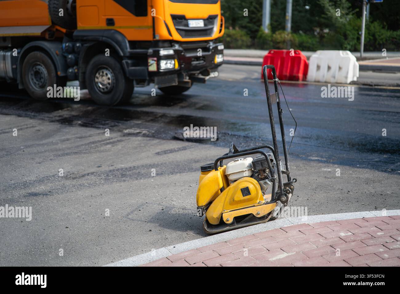 Attrezzatura compattatrice a piastra vibrante sull'asfalto stradale durante la riparazione della strada Foto Stock