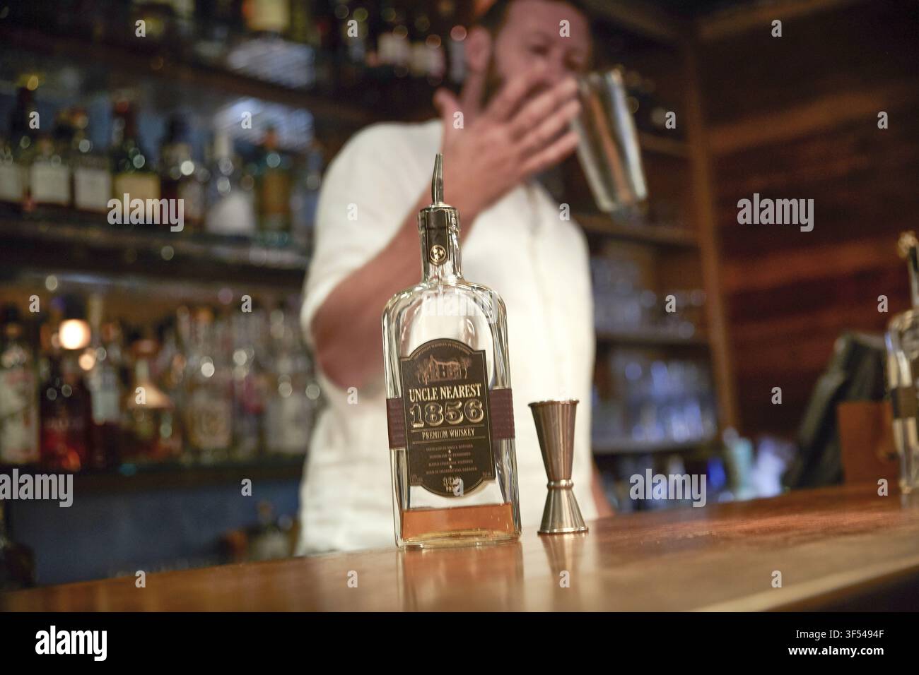 Un barista mescola un drink dietro una bottiglia di whisky premium Uncle Nearest 1856 in un bar a Londra, Inghilterra, Regno Unito, il 16 luglio 2018. Foto Stock