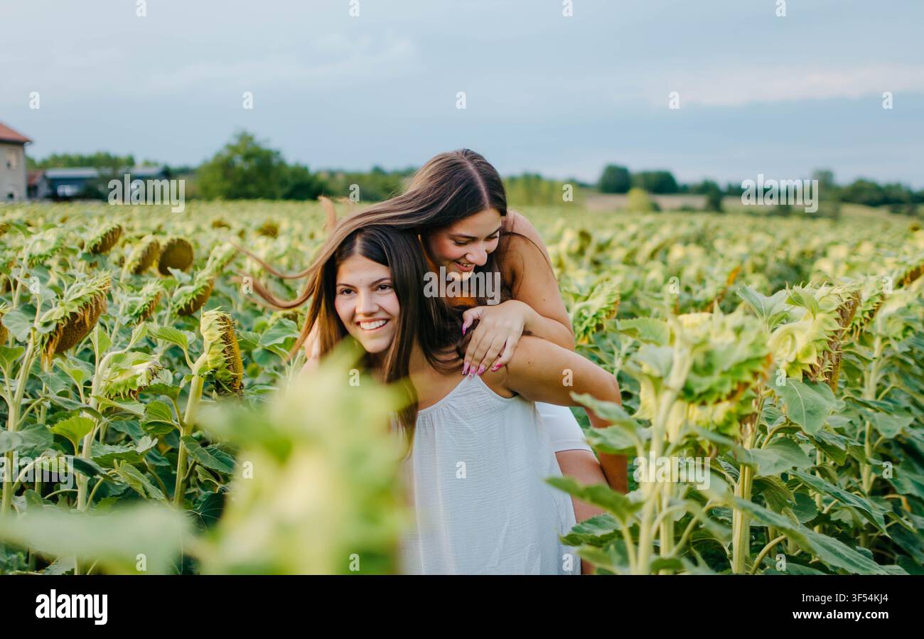 Due belle giovani donne che si divertono in un girasole Foto Stock