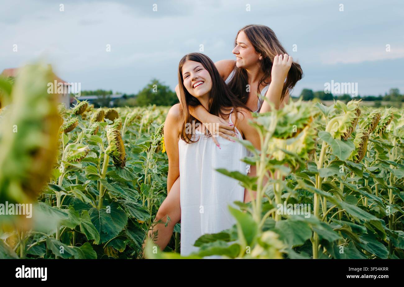 Due belle giovani donne che si divertono in un girasole Foto Stock
