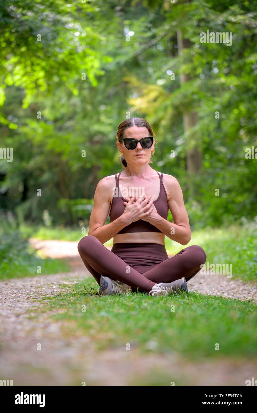 donna in forma seduta in meditazione e che pratica yoga in una foresta Foto Stock