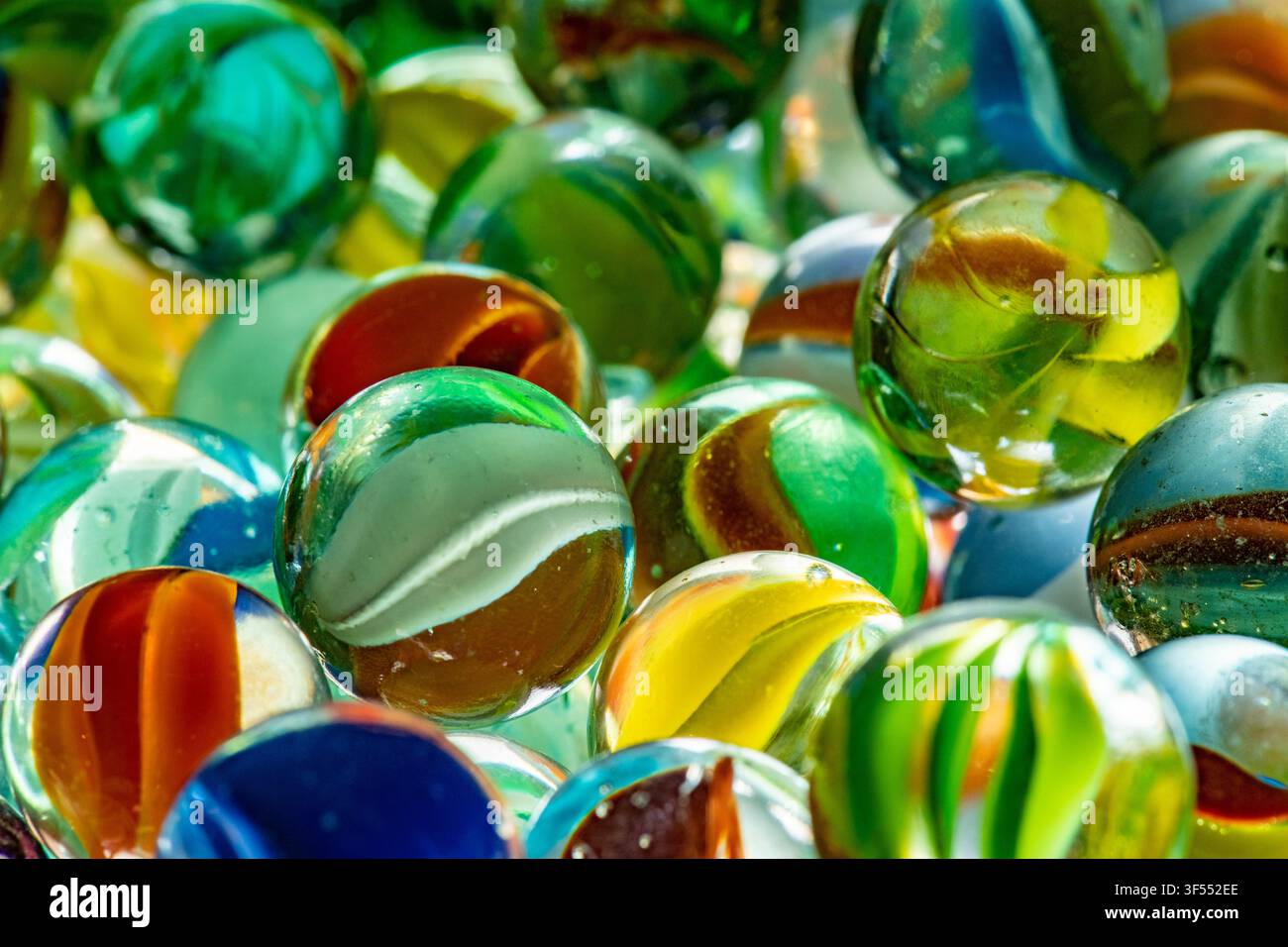 Molte biglie di vetro colorate che creano uno sfondo vivace e giocoso Foto Stock