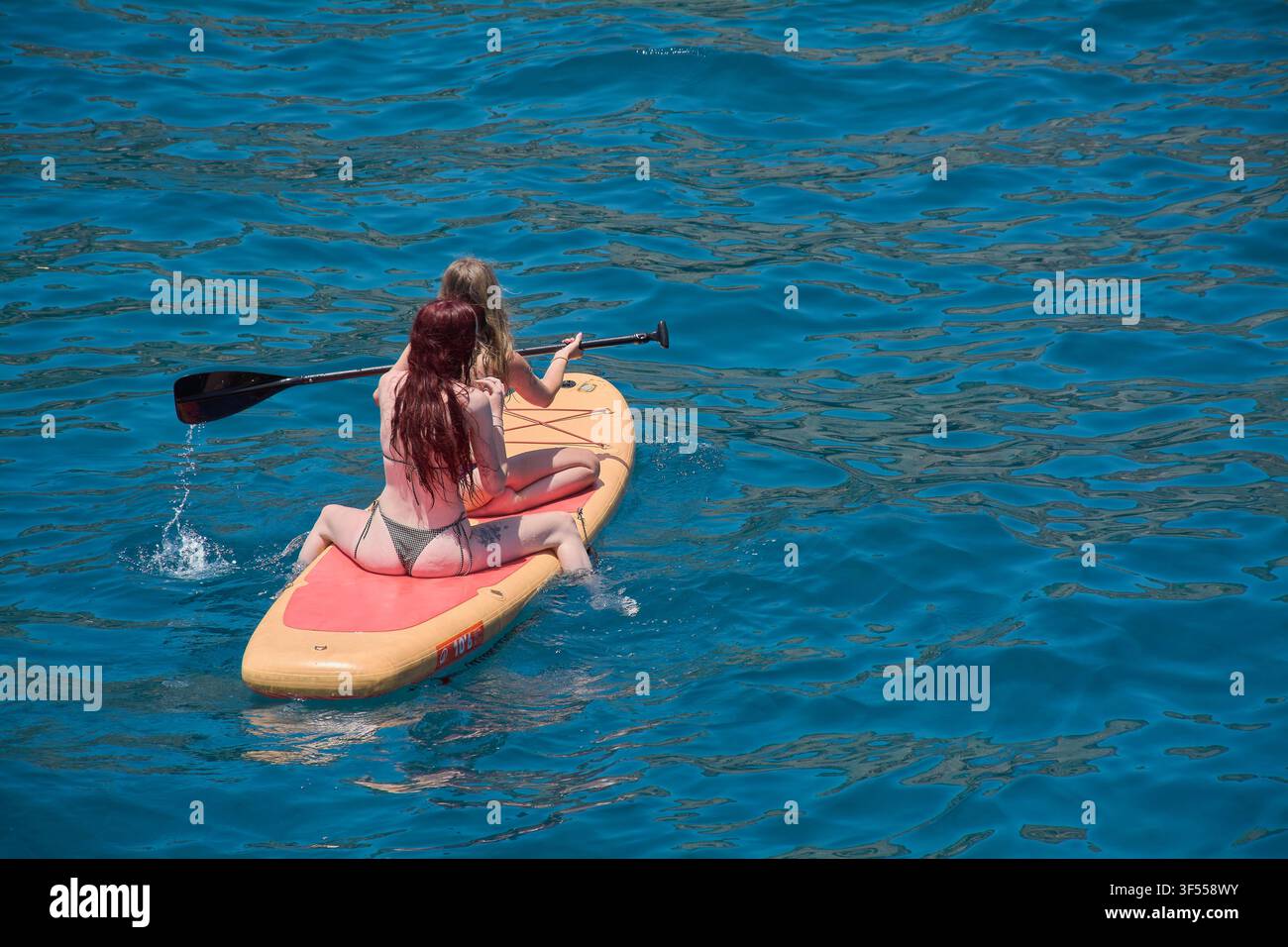 Gran Canaria, Spagna – 31 luglio 2026: Veduta aerea di amici che si divertono a fare stand up paddle in acque marine limpide. Foto Stock
