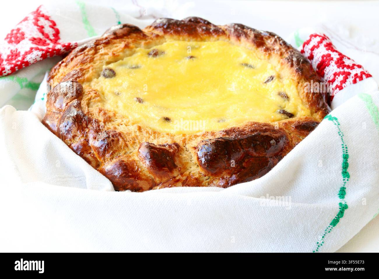 Pane dolce tradizionale pasquale ripieno di formaggio fresco e uvetta, avvolto in un asciugamano ricamato. Foto stock per concetti di pasticceria e festività. Foto Stock