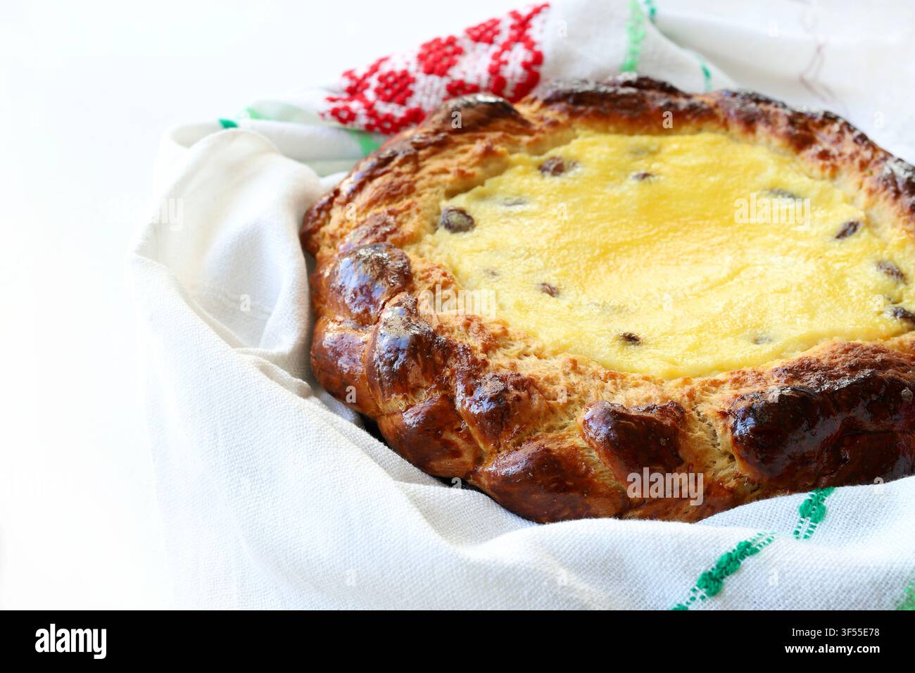 Pane dolce tradizionale pasquale ripieno di formaggio fresco e uvetta, avvolto in un asciugamano ricamato. Foto stock per concetti di pasticceria e festività. Foto Stock