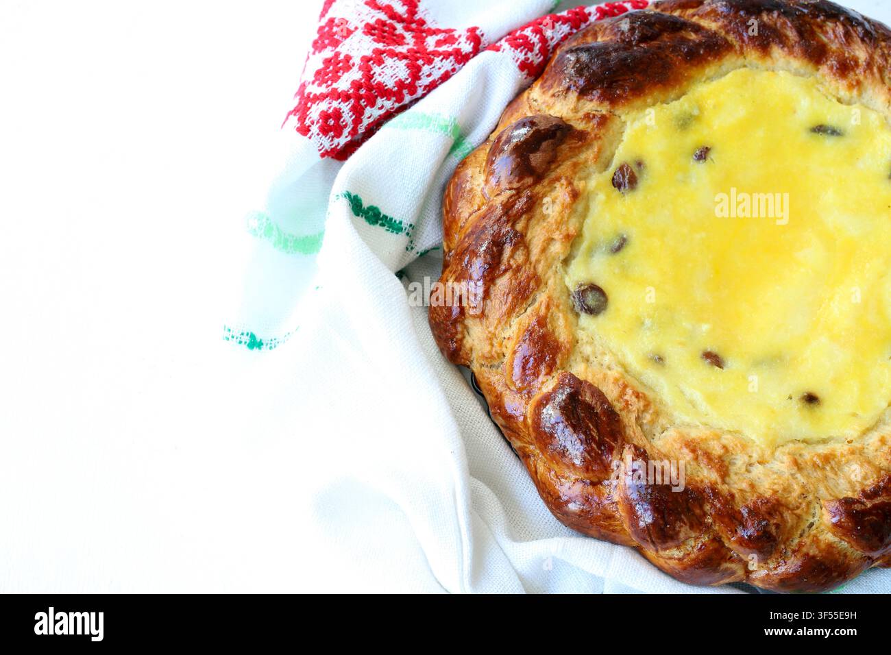 Pane dolce tradizionale pasquale ripieno di formaggio fresco e uvetta, avvolto in un asciugamano ricamato. Foto stock per concetti di pasticceria e festività. Foto Stock