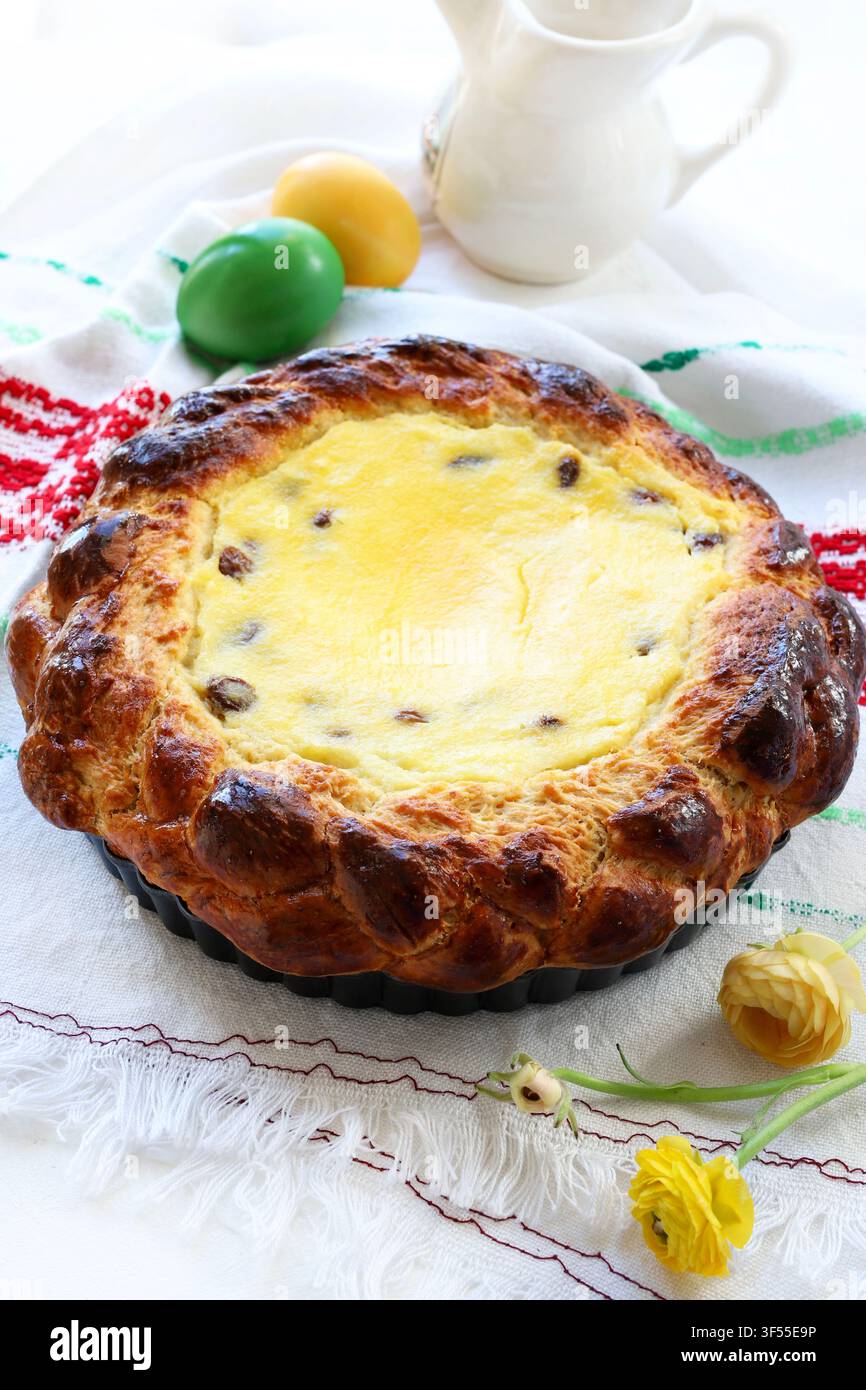Tradizionale torta pasquale rumena Pasca con formaggio dolce e uvetta, decorata con uova colorate e fiori primaverili. Tradizione pasquale dell'Europa dell'Est Foto Stock