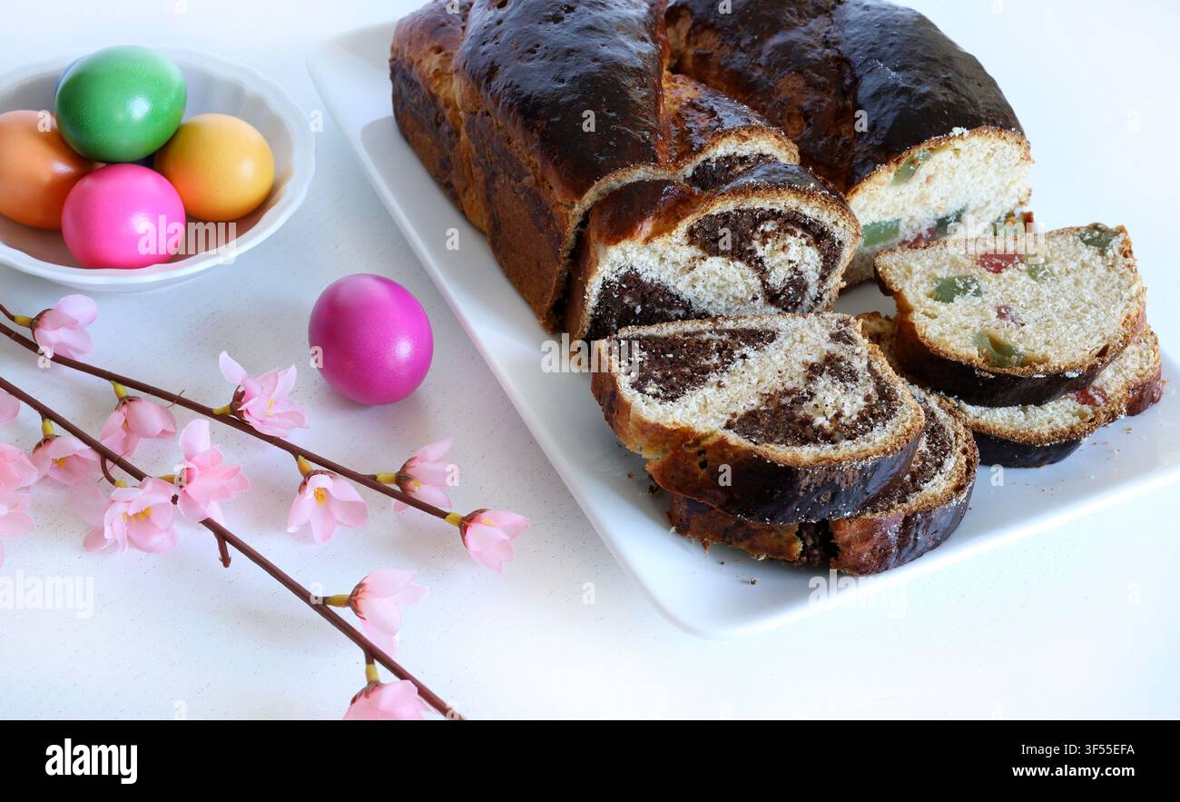 Cozonac rumeno tradizionale con noci, spirale di cacao e Turkish delight. Pane dolce affettato con uova colorate festive. Foto Stock