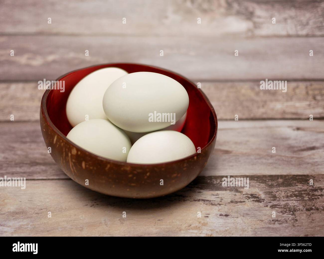 Uova di anatra fresche in una ciotola di cocco su sfondo di legno rustico. Foto Stock