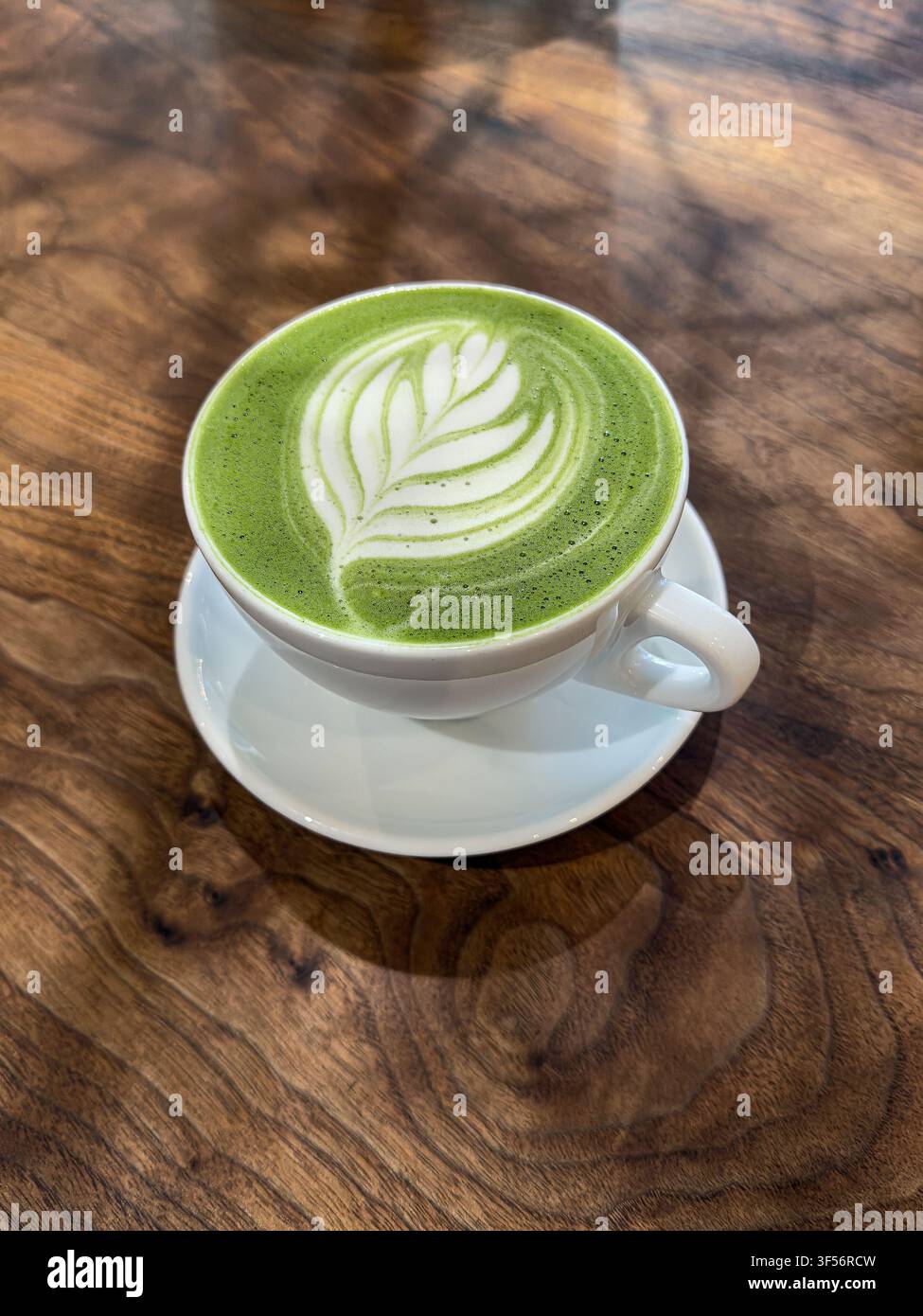 Vista ad angolazione alta di una tazza di latte al tè verde matcha su un tavolo a grana di legno Foto Stock