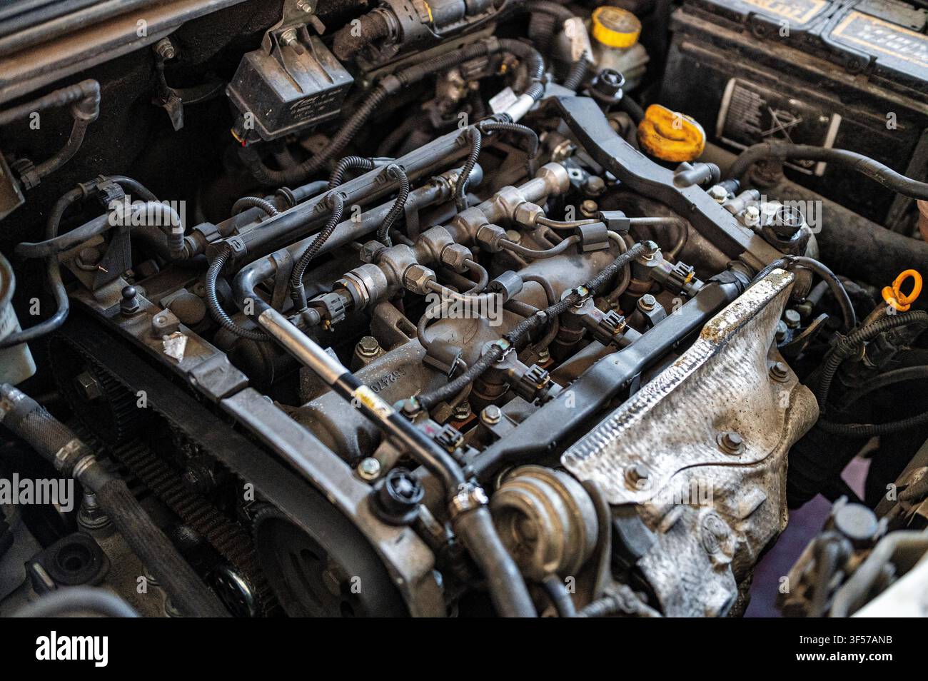 Motore dell'auto e componenti meccanici visibili sotto il cofano, che mostrano il sistema di iniezione del carburante, il cablaggio, i tubi e le parti del motore durante la manutenzione automobilistica Foto Stock