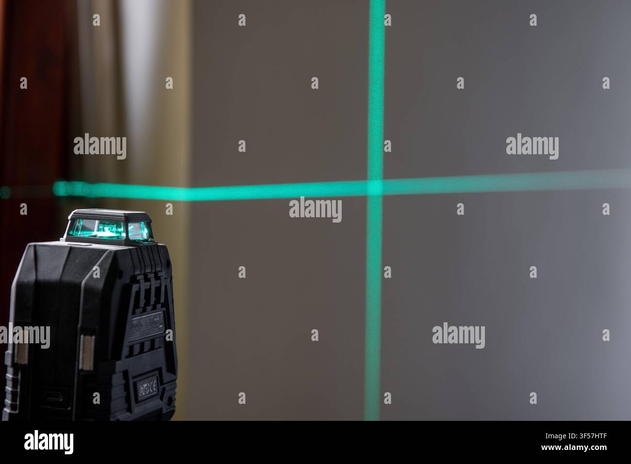 Un livello laser montato su un treppiede proietta una linea verde su un muro di costruzione. Un livello laser è essenziale per allineamenti e misurazioni precise. Foto Stock