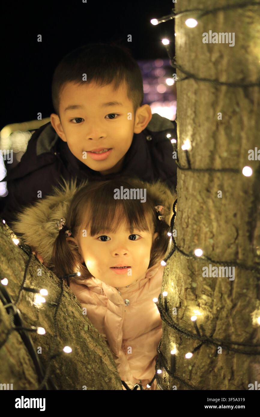 Illuminazione natalizia e fratello e sorella giapponesi (ragazzo di 8 anni e bambina di 3 anni) Foto Stock