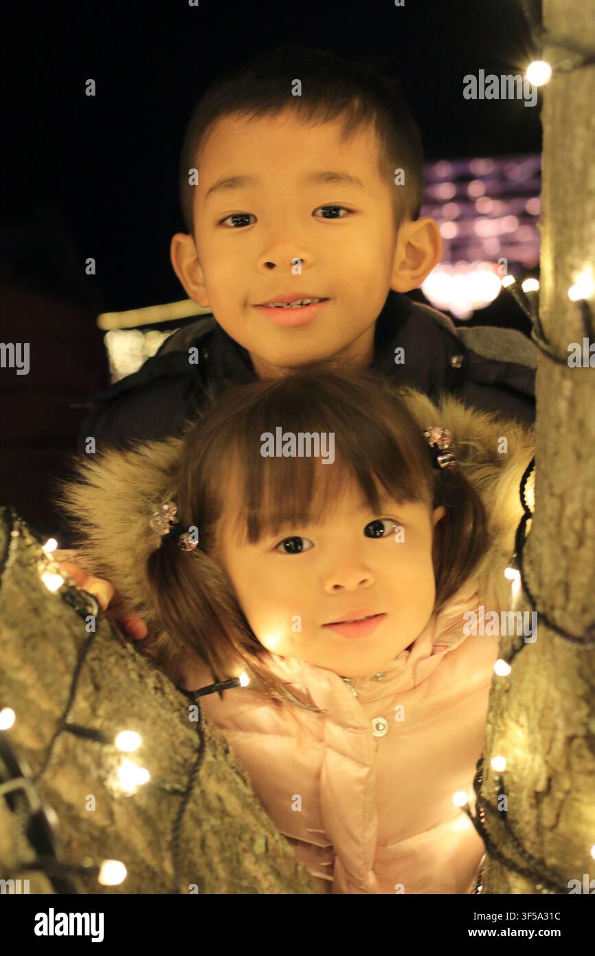 Illuminazione natalizia e fratello e sorella giapponesi (ragazzo di 8 anni e bambina di 3 anni) Foto Stock