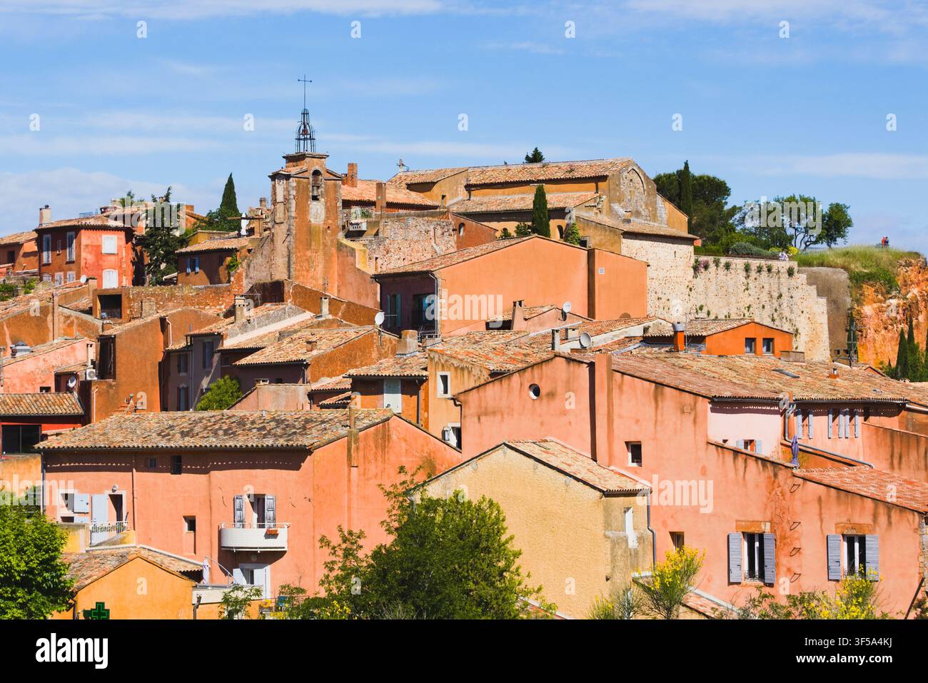 Case tradizionali color ocra terracotta e campanile della chiesa nel villaggio collinare di Roussillon, Provenza, Francia. Foto Stock