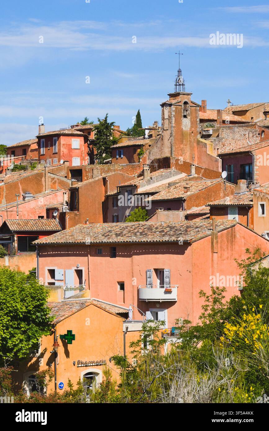 Gruppo di case tinte di ocra e un campanile storico nel villaggio collinare di Roussillon, Provenza, Francia. Foto Stock