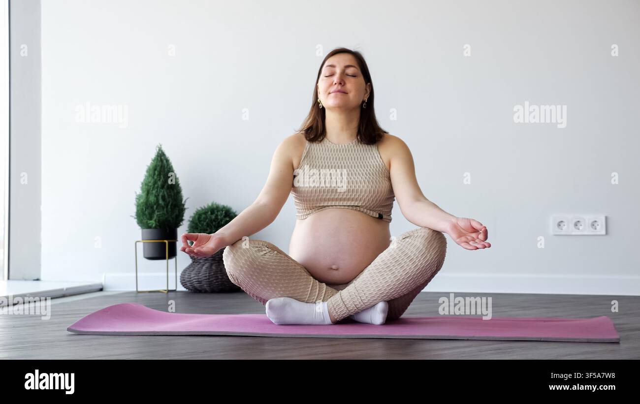 Donna incinta in meditazione nella posizione del loto che gode della pratica dello yoga prenatale Foto Stock