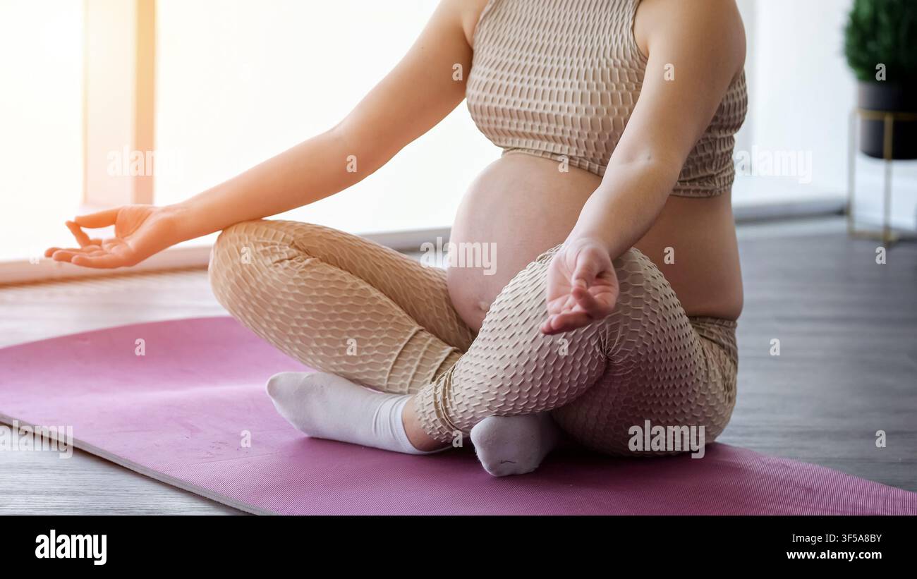 Donna incinta che pratica yoga e meditazione per il benessere Foto Stock