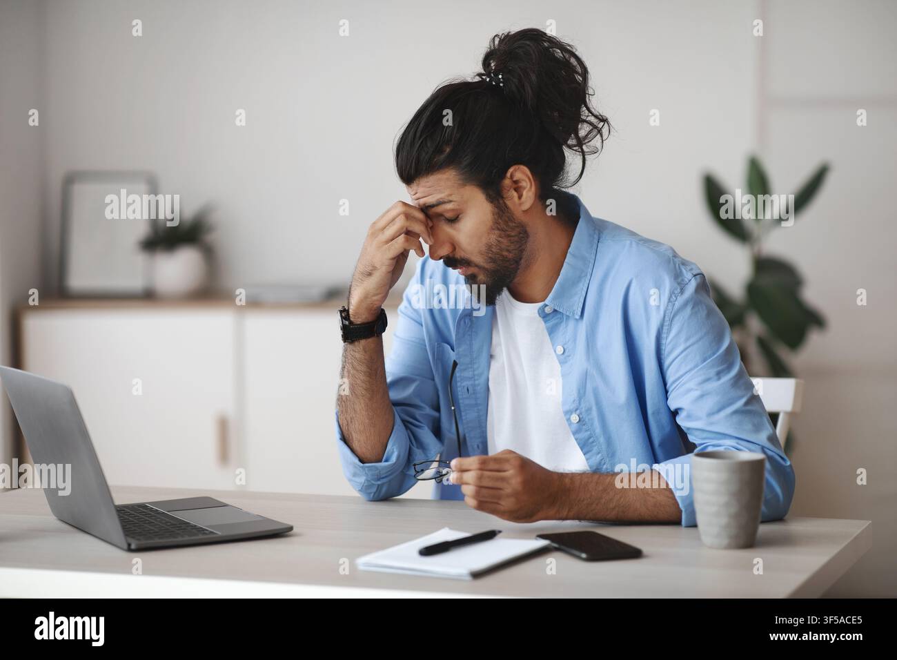 Affaticamento degli occhi. Ha sottolineato Indian Man stanco dopo aver lavorato su laptop in ufficio Foto Stock