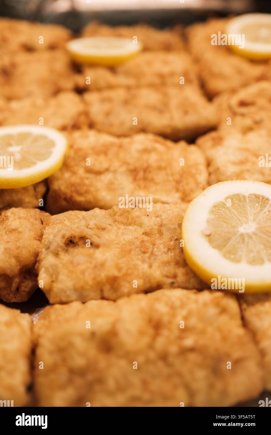 Filetti di pesce panati cotti, guarniti con limone fresco per un pasto delizioso Foto Stock