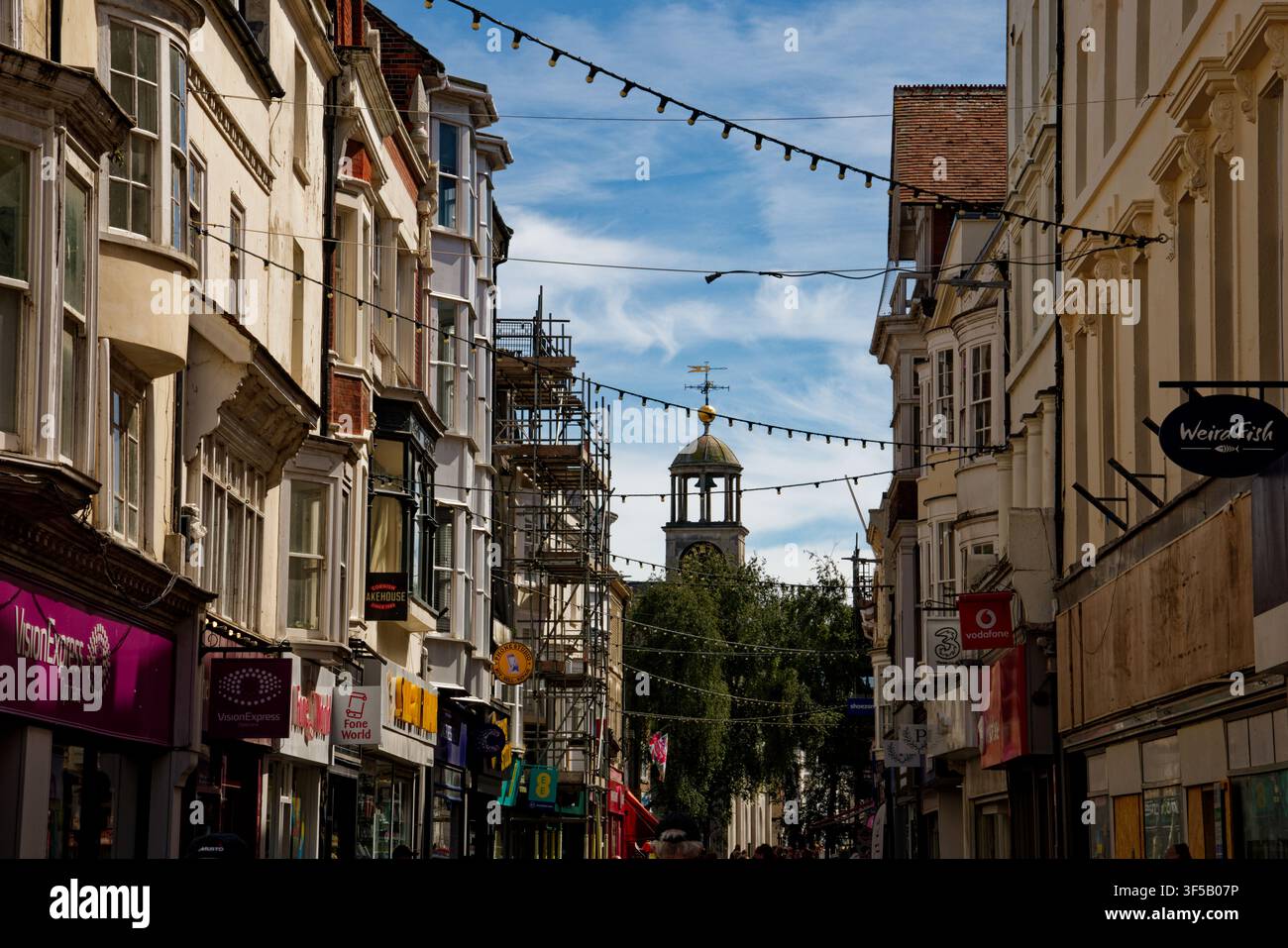Edifici lungo una via dello shopping del centro cittadino con torre dell'orologio ornata, Weymouth, Dorset, Inghilterra. Foto Stock