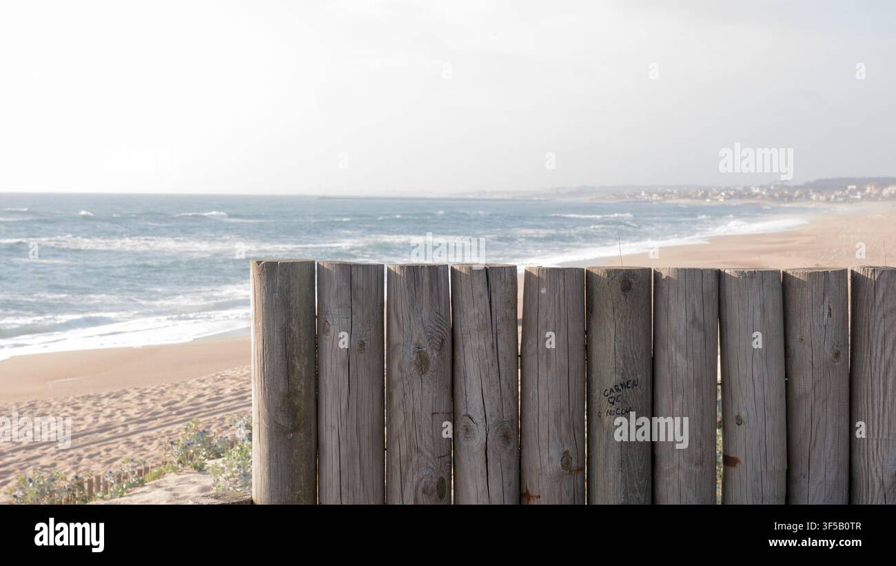 Ringhiera in legno stagionato su una passerella che si affaccia su una vasta spiaggia di sabbia deserta e sulle onde atlantiche che si infrangono, Portogallo — Passeggiata costiera, vista sul mare e fuga tranquilla Foto Stock