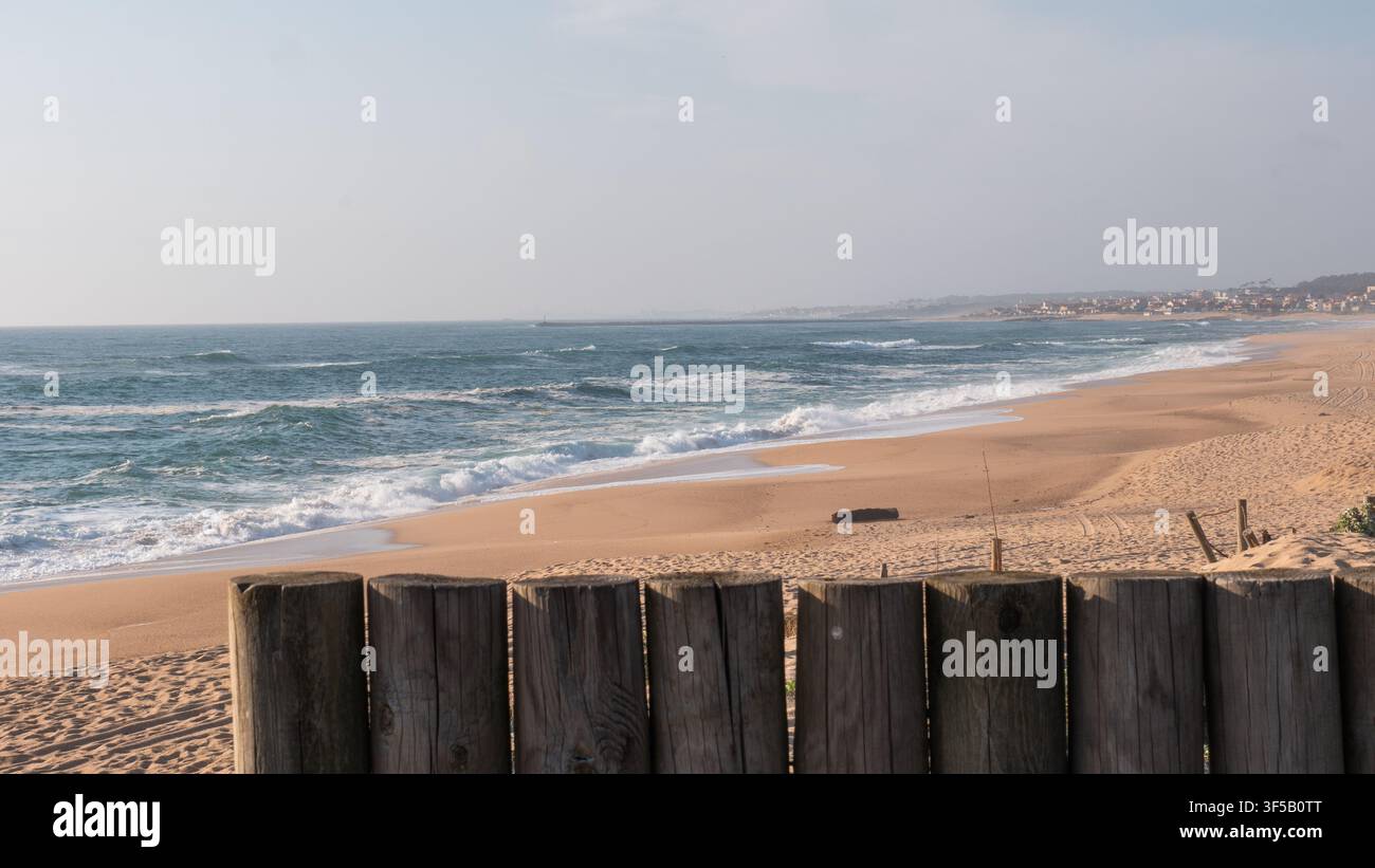 Ringhiera in legno stagionato su una passerella che si affaccia su una vasta spiaggia di sabbia deserta e sulle onde atlantiche che si infrangono, Portogallo — Passeggiata costiera, vista sul mare e fuga tranquilla Foto Stock