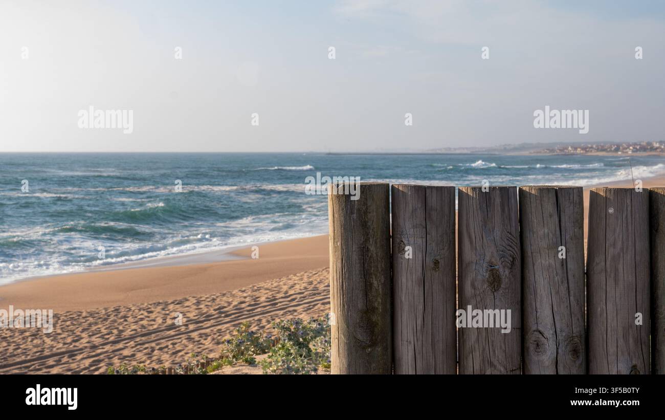 Ringhiera in legno stagionato su una passerella che si affaccia su una vasta spiaggia di sabbia deserta e sulle onde atlantiche che si infrangono, Portogallo — Passeggiata costiera, vista sul mare e fuga tranquilla Foto Stock