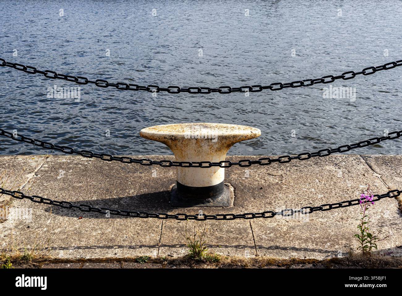 Bollardo di ormeggio e catene al bordo del porto canale Foto Stock