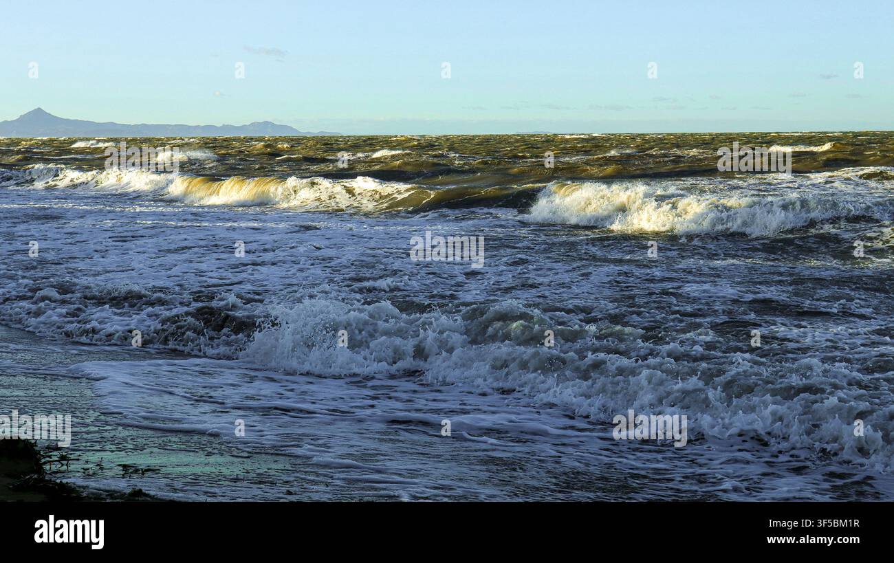 Le acque scure si alzano e si schiantano violentemente contro la riva mentre le nuvole di tempesta si addensano sul Mar Mediterraneo, creando un'atmosfera drammatica e intensa d Foto Stock