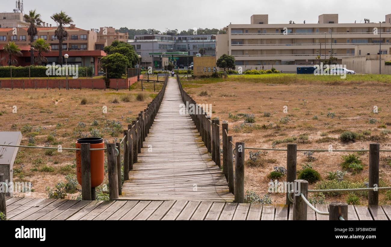 Passeggiata in legno che si estende verso l'interno attraverso una duna protetta verso i blocchi di appartamenti costieri, Nord Portogallo — Concetto: Pressione dello sviluppo costiero Foto Stock