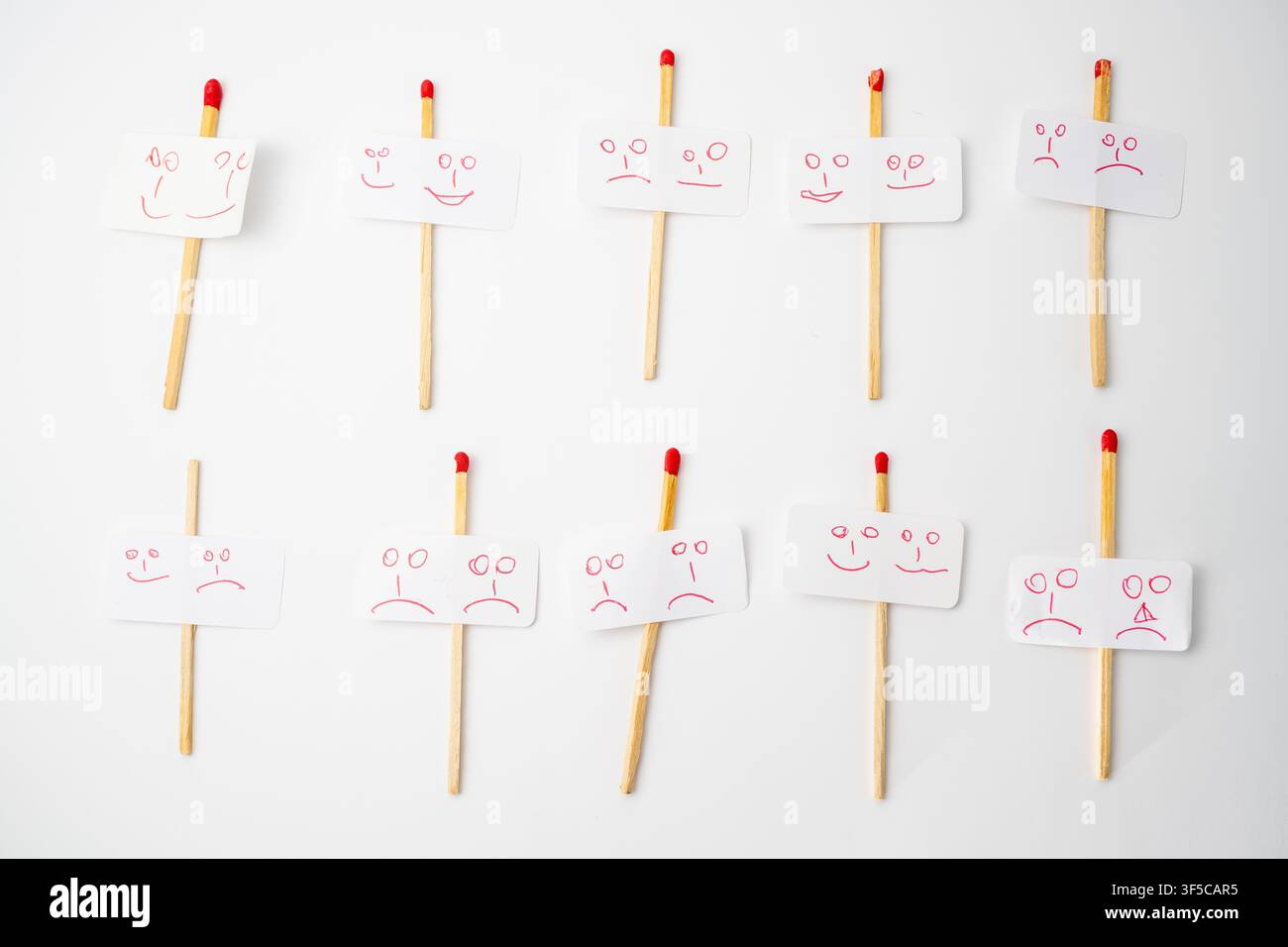 Concetto creativo di intelligenza emotiva e lavoro di squadra con personaggi fatti a mano con bastoncini di legno che mostrano espressioni facciali diverse su sfondo bianco Foto Stock