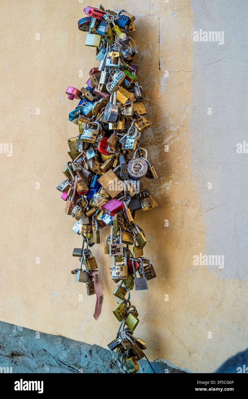 Un grande ammasso di catene di lucchetti colorati lasciati dalle coppie sul Ponte Vecchio a Firenze, Italia. La fotografia cattura le iscrizioni sui lucchetti, metallico Foto Stock