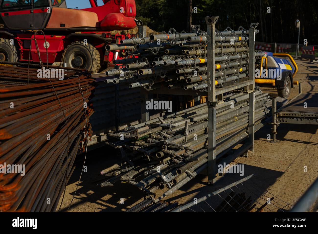 Attrezzature per impalcatura impilate e barre d'acciaio arrugginite in un cantiere industriale sotto il sole, struttura metallica, rinforzo in cemento, stoccaggio di materiali da costruzione, area di stoccaggio del cantiere Foto Stock