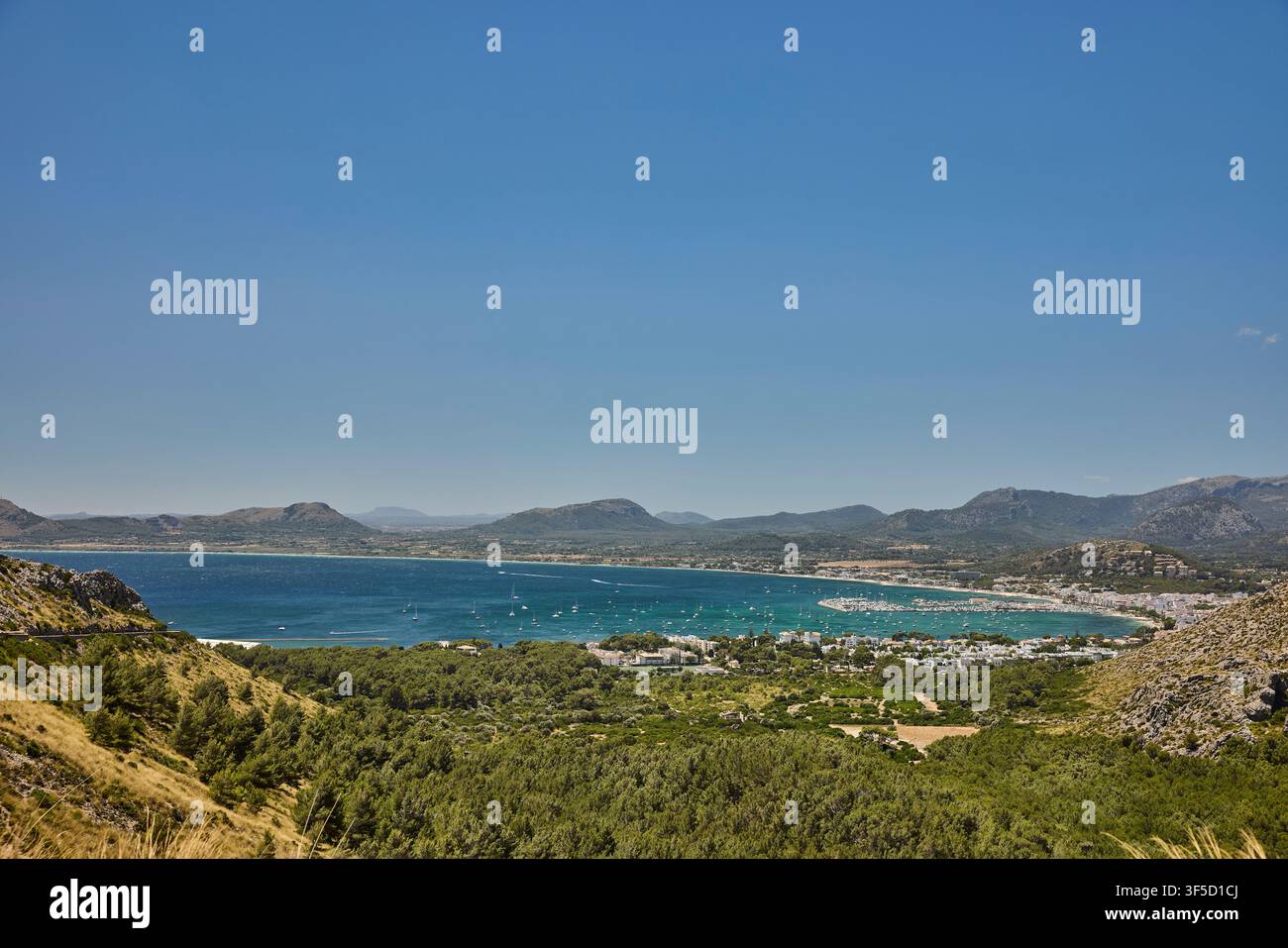 Baia di Port de Pollença con barche ancorate e montagne circostanti sotto un cielo blu terso Foto Stock